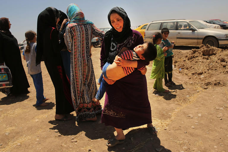 Iraki nő karjaiban kimerült gyermekével menekül Mosul városából, miután az Iszlám Állam harcosai elfoglalták a várost. (Fotó: Spencer Platt/Getty Images)