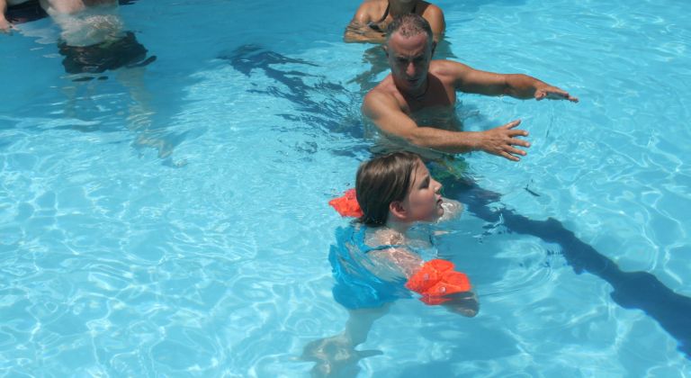 Pali úszni tanítja Dorkát (ez a küldetés még senkinek sem sikerült).