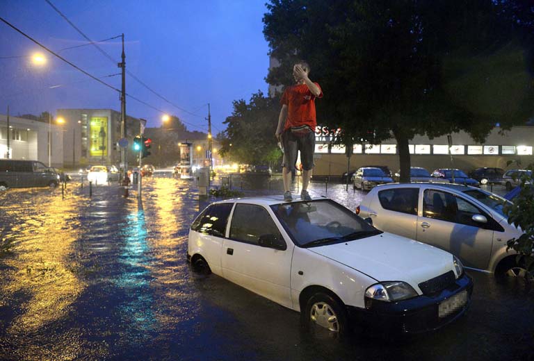 Egy férfi áll elakadt autója tetején a vízzel elöntött XIII. kerületi Béke térnél (Fotó: MTI/Bruzák Noémi)