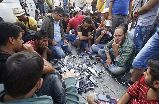 Várakozó illegális bevándorlók mobiltelefonjaikat töltik a budapesti Keleti pályaudvar előtt, MTI Fotó: Balogh Zoltán