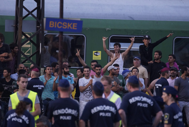 Rendőrök az illegális bevándorlókkal a budapesti Keleti pályaudvarról Sopronba közlekedő, Bicskén megállított vonat mellett 2015. szeptember 3-án. A migránsok főként az állomáson veszteglő vonaton van