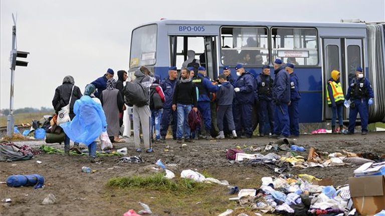 Rendőrök biztosítják az illegális bevándorlókat szállító buszt a Röszke melletti gyűjtőponton, a magyar-szerb határ közelében 2015. szeptember 11-én. MTI Fotó: Molnár Edvárd