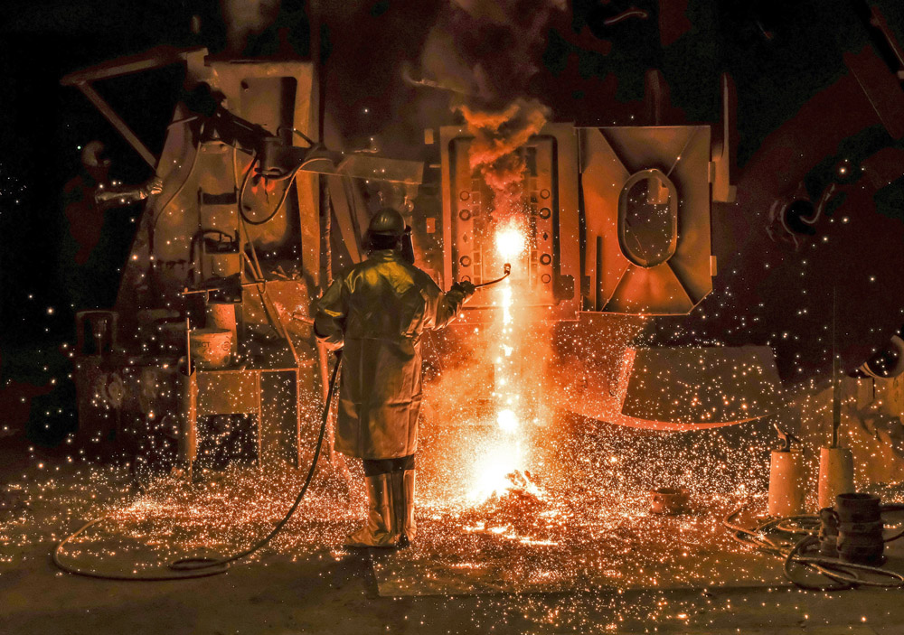 Egy munkás egy izzó acéldarabot távolít el egy kemencéből a Salzgitter acélipari vállalat kohójában