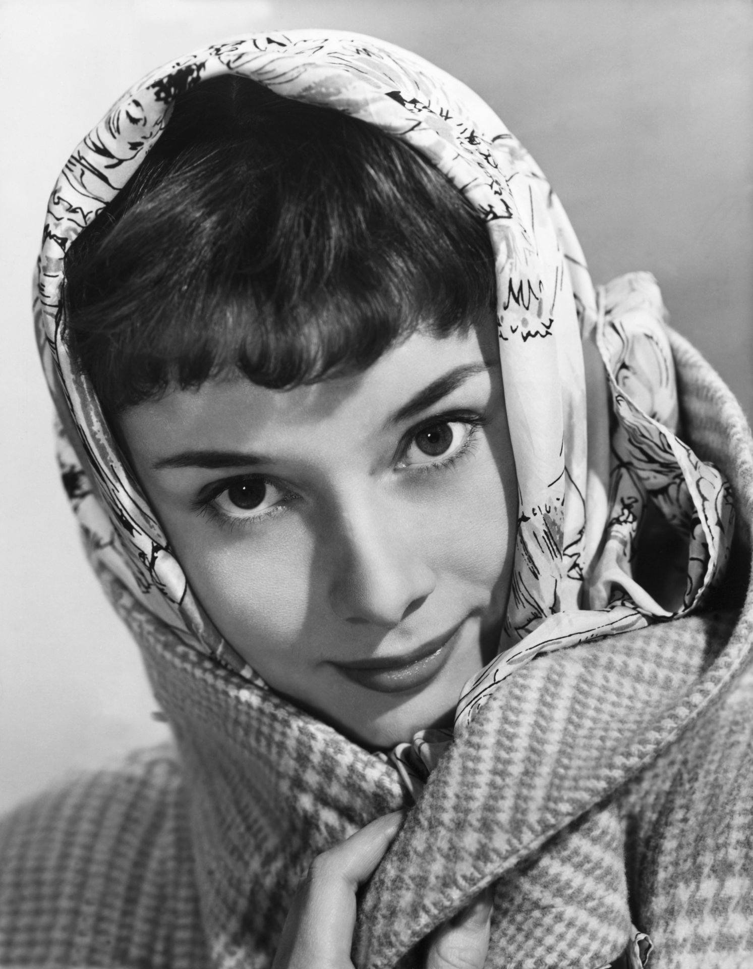 Audrey Hepburn fejkendős, kabátos fotója.