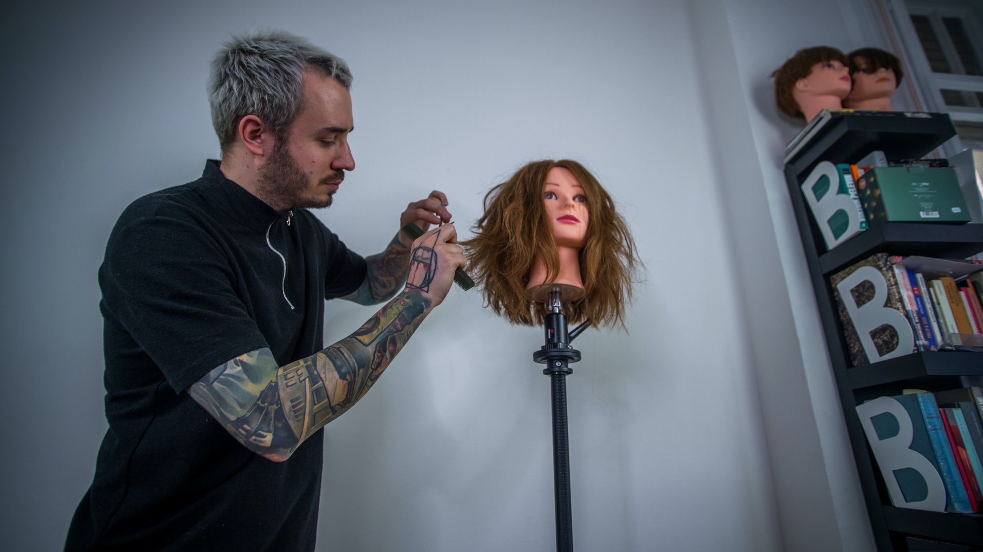 A koronavírus-járvány miatt önkéntes karanténban lévő fodrász oktatóvideót készít egy gyakorlásra használt babafej haját vágva budapesti otthonában 2020. március 26-án (Fotó: MTI/Balogh Zoltán)
