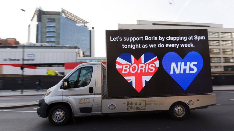 Boris Johnson brit miniszterelnököt és a a brit állami egészségügyi szolgálatot támogató üzenet egy kisteherautó oldalán Londonban - Fotó:&nbsp;MTI/EPA/Vickie Flores