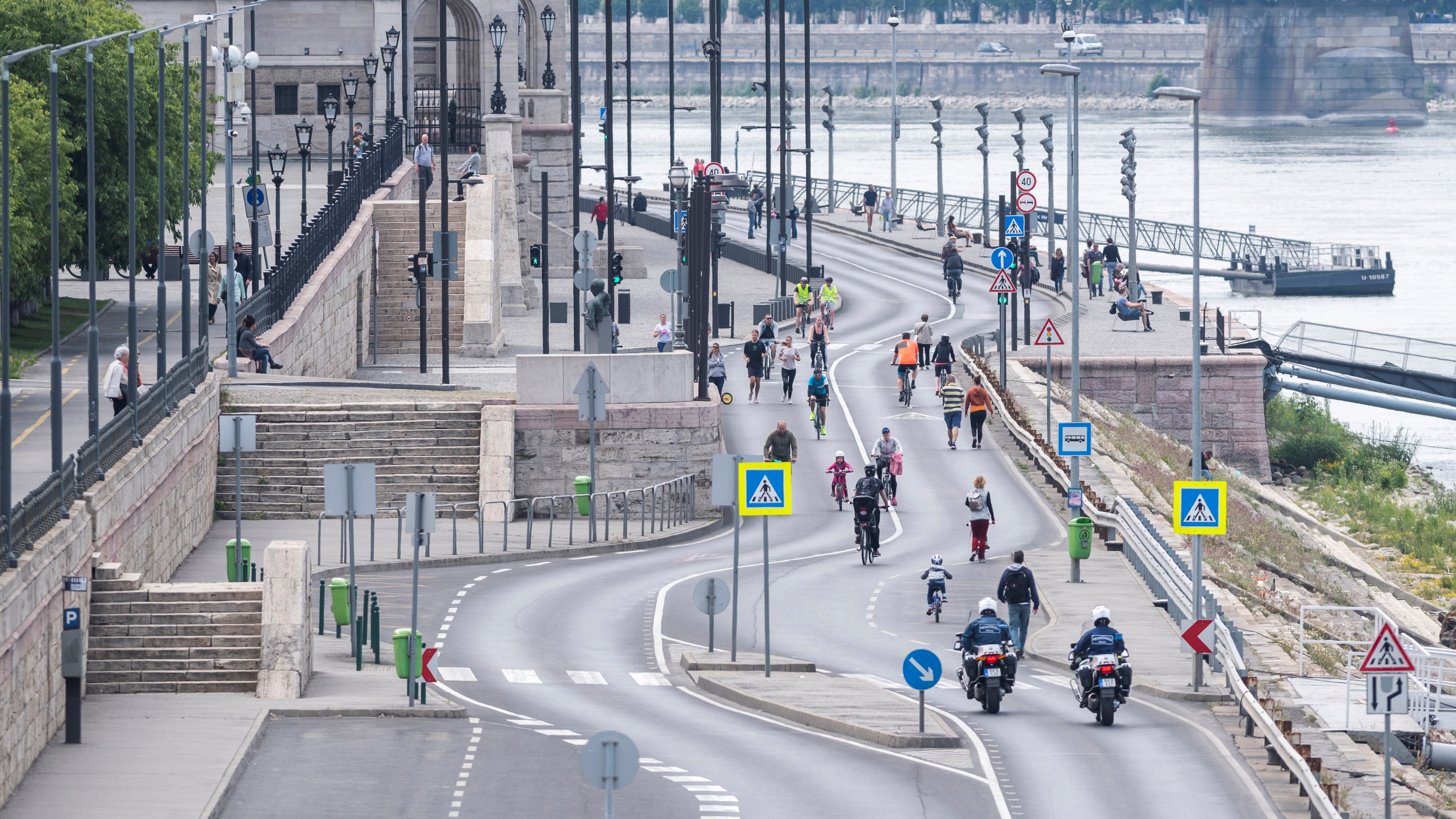 Kerékpárosok és gyalogosok közlekednek a gépjárműforgalom elől a hétvégére lezárt pesti alsó rakparton, előtérben motoros rendőrök 2020. május 16-án.