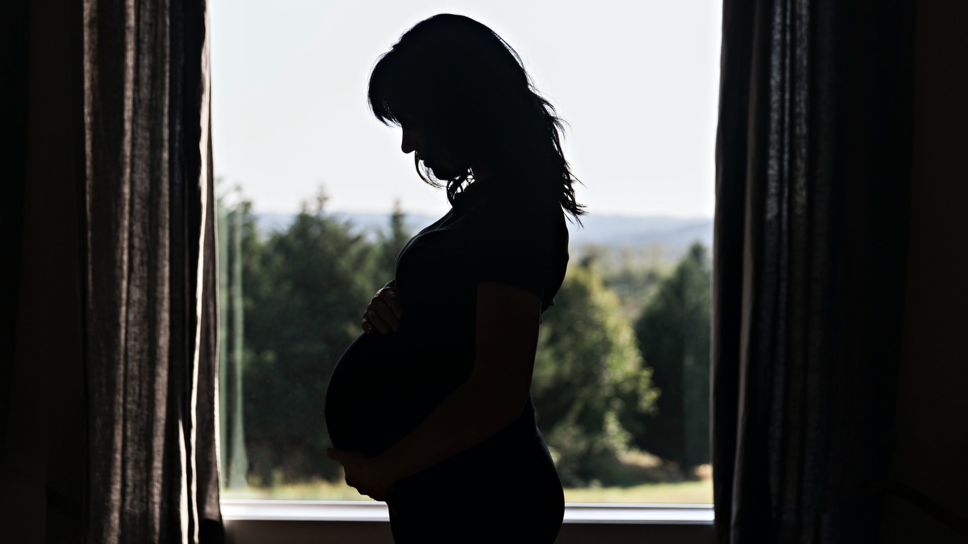 Terhes nő egy ablak előtt