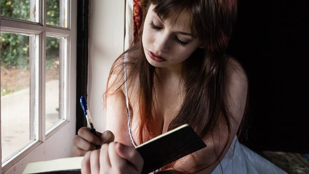 nő naplót ír egy ablakban