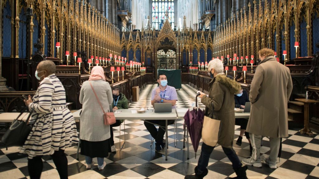 Emberek érkeznek a koronavírus elleni oltás felvételére a londoni Westminster-apátságban kialakított oltóközpontban 2021. március 10-én. 