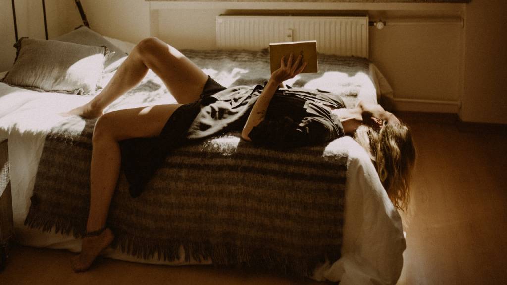 nő magányosan egy ágyon olvas
