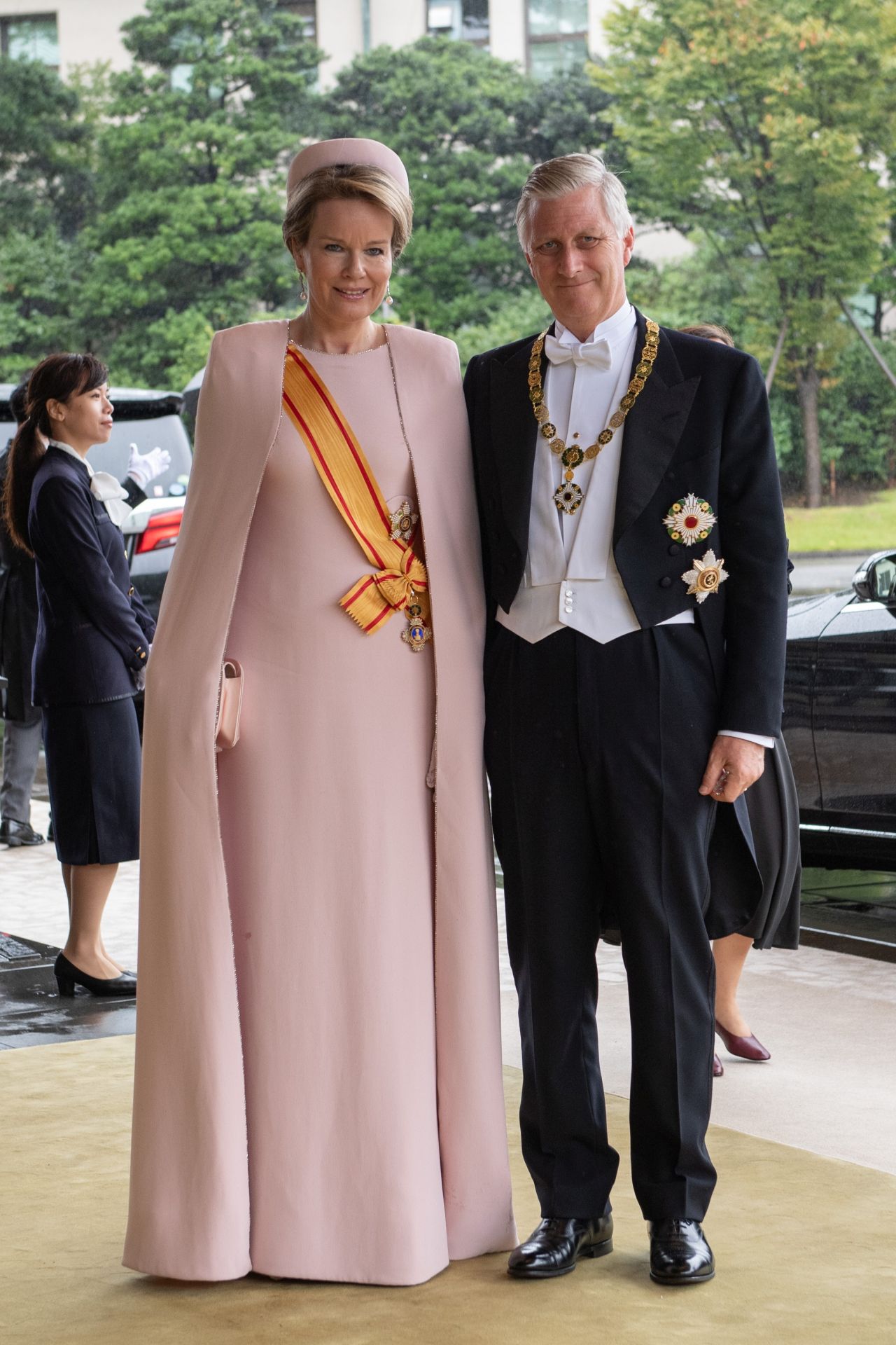 Matild belga királynén 2019-ben, Tokióban láthattuk ezt a halvány rózsszín, köpennyel kombinált alkalmi ruhát.