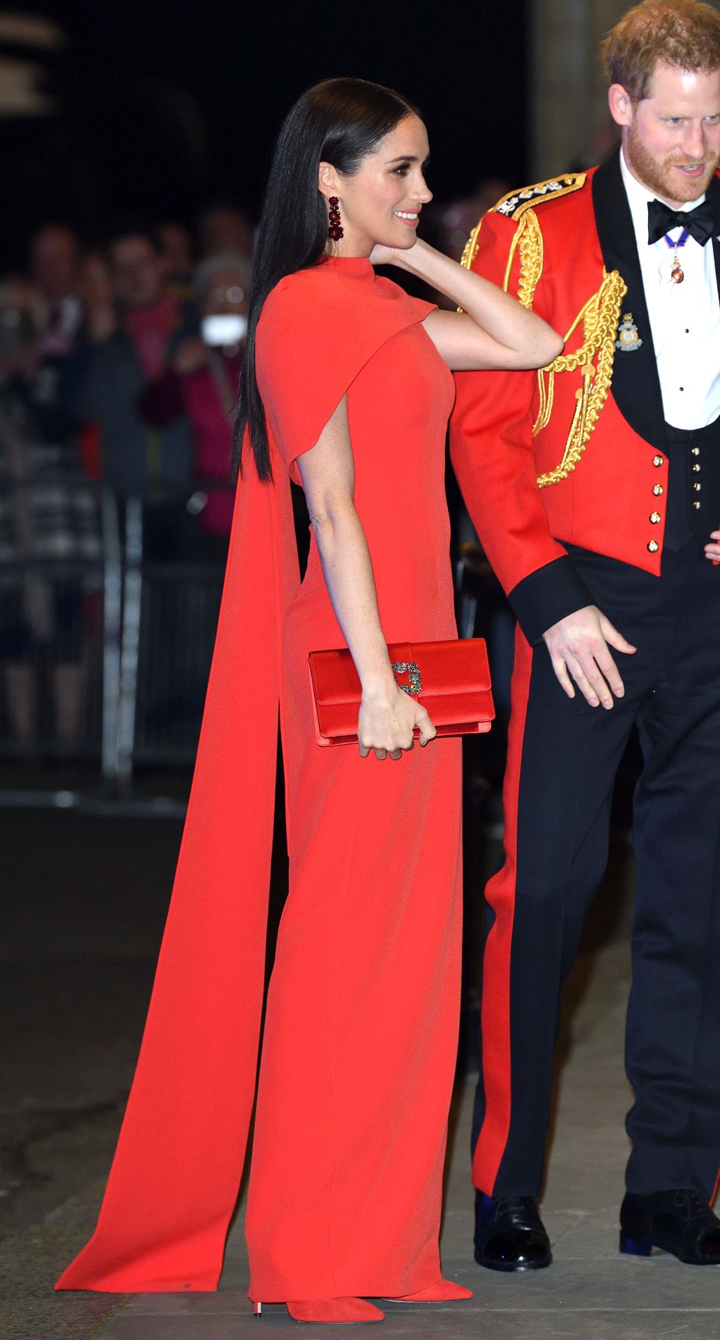 Meghan Markle piros Safiyaa köpennyel kombinált estélyi ruhában a Mountbatten Festival of Music eseményen 2020-ban, a Royal Albert Hallban.