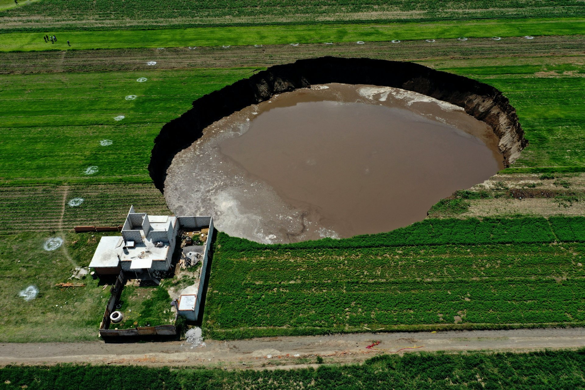 Kis híján egy házat is elnyelt a hatalmas víznyelő, amely a mexikói Santa Maria Zacatepec településen jelent meg 2021. május 30-án (Fotó: JOSE CASTAÑARES / AFP)