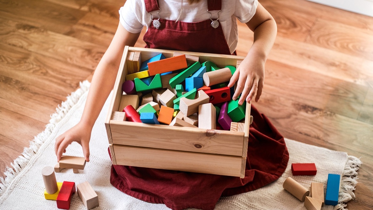 Little girl cleaning up the toy box at home. Child's space organization.