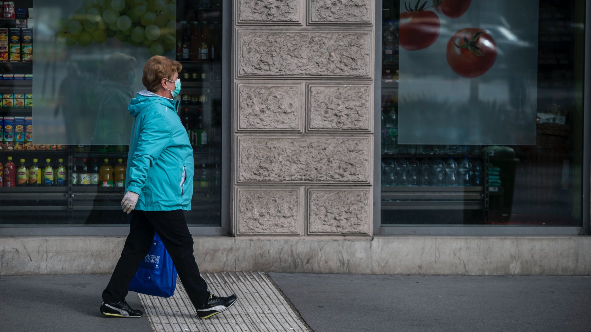 Maszkot viselő idős nő sétál Budapesten