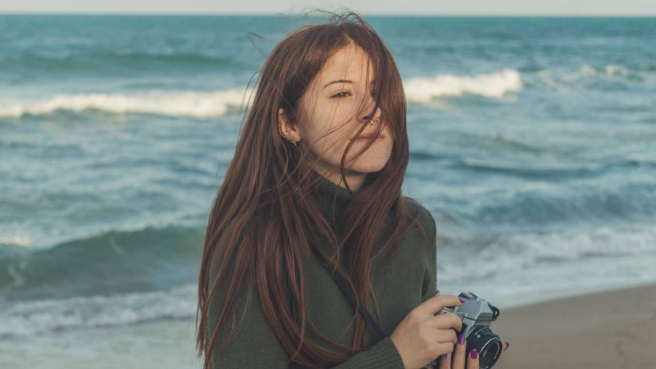 nő tengerparton fényképezővel