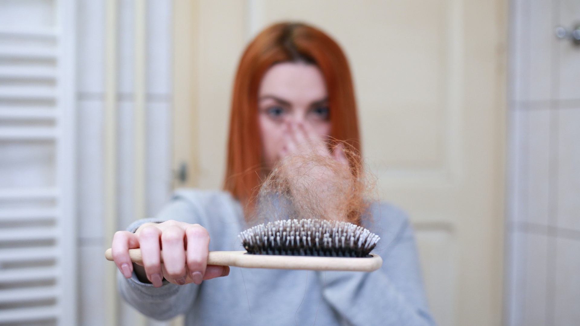 Kétségbeesett nő mutatja a kihullot haját a hajkefén