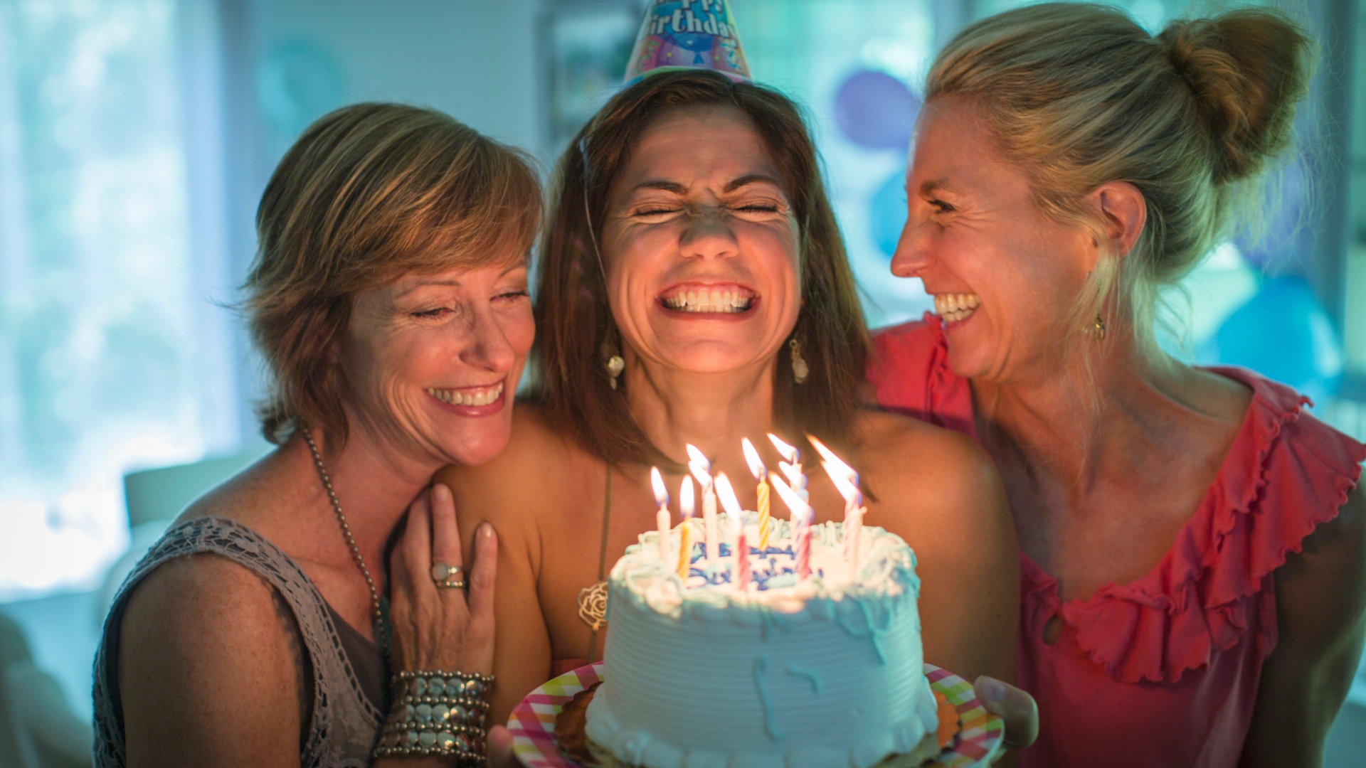 Három középkorú nő születésnapi tortával