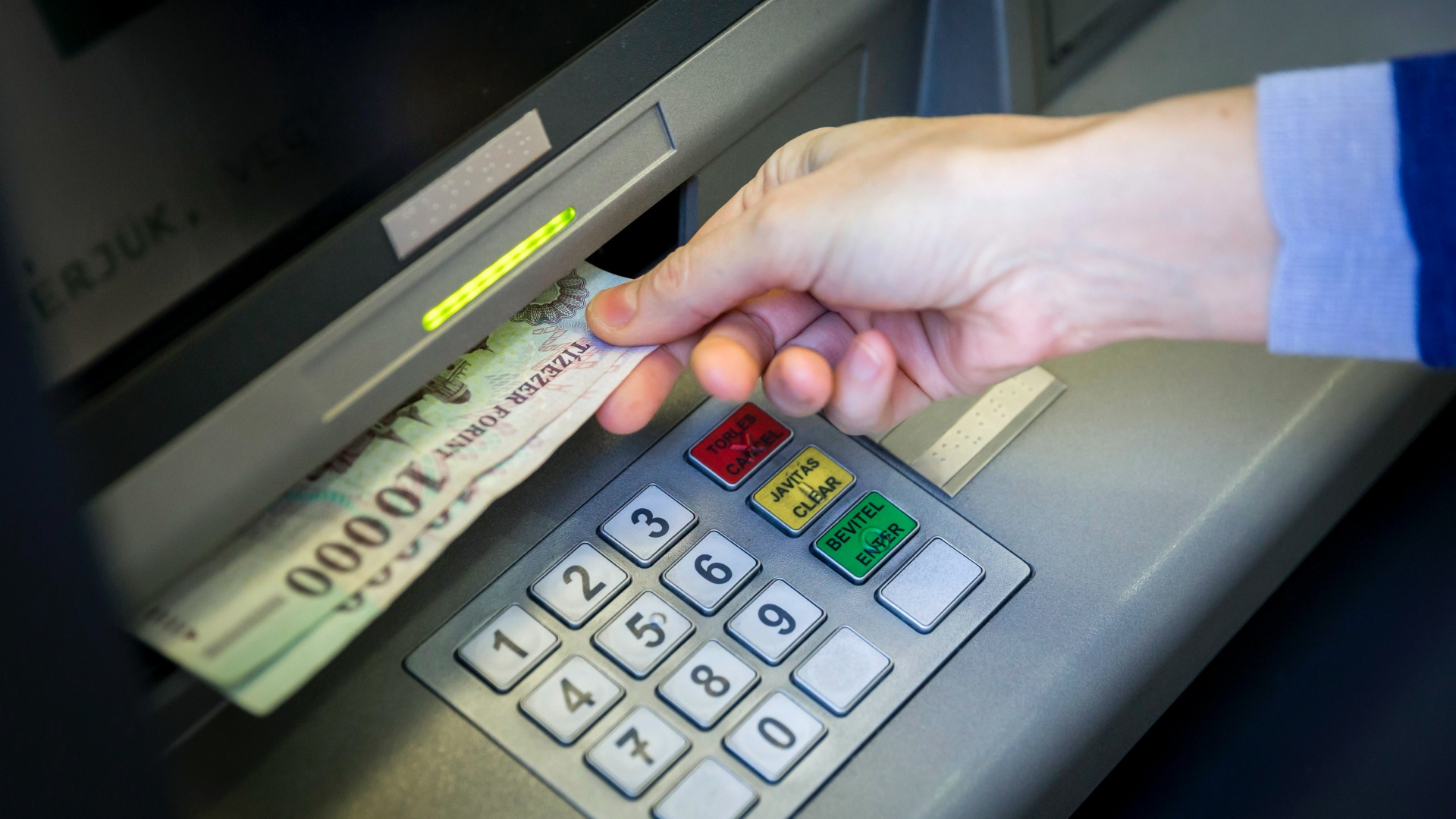 Bankjegyeket vesz ki egy pénzkiadó automatából (ATM) egy ügyfél a Sberbank központi bankfiókjában Budapesten, a Rákóczi úton 2014. március 25-én.