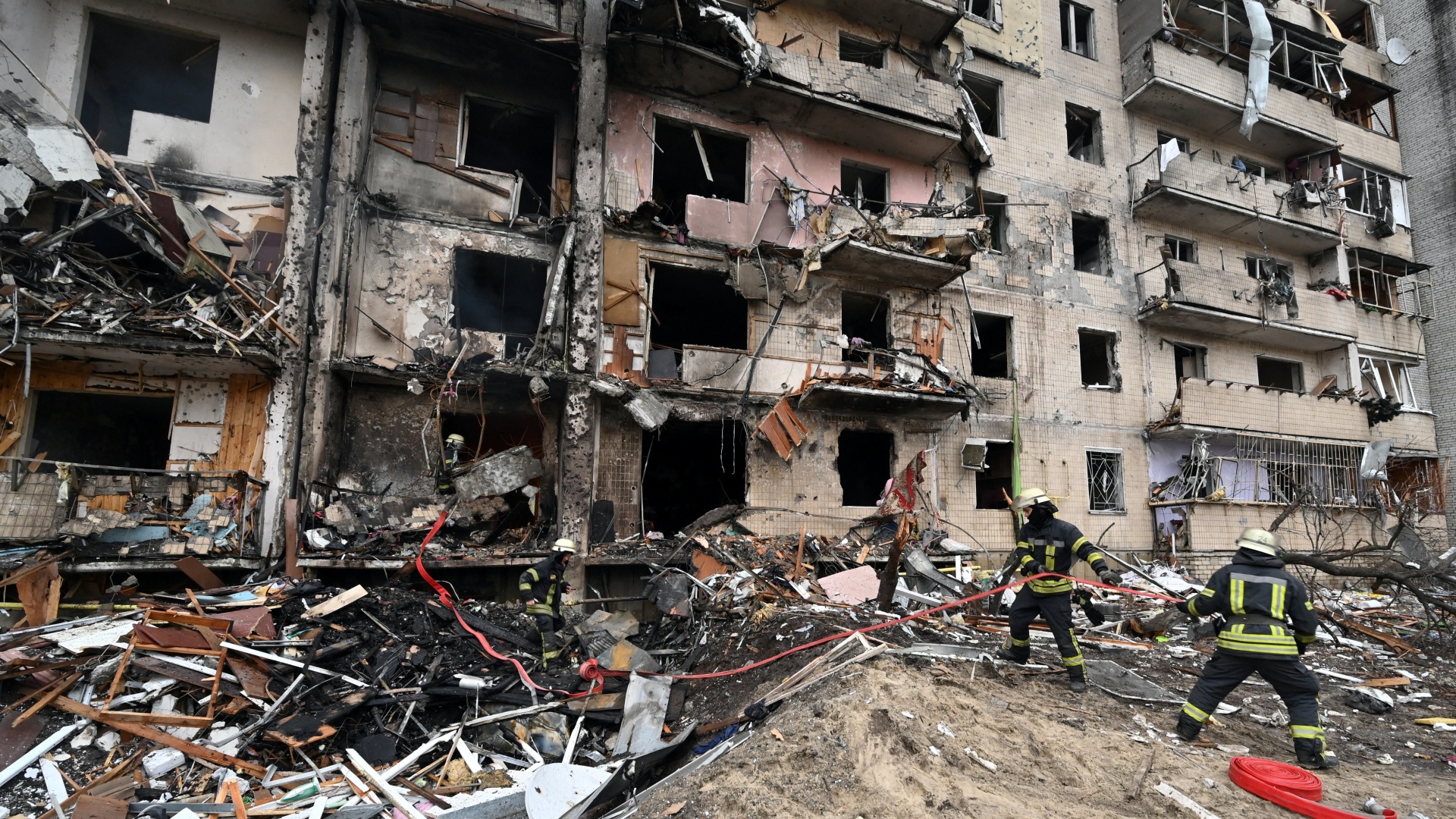 Tűzoltók dolgoznak egy megrongálódott lakóháznál az ukrán főváros, Kijev egyik külvárosában, ahol egy rakéta csapódott be 2022. február 25-én.