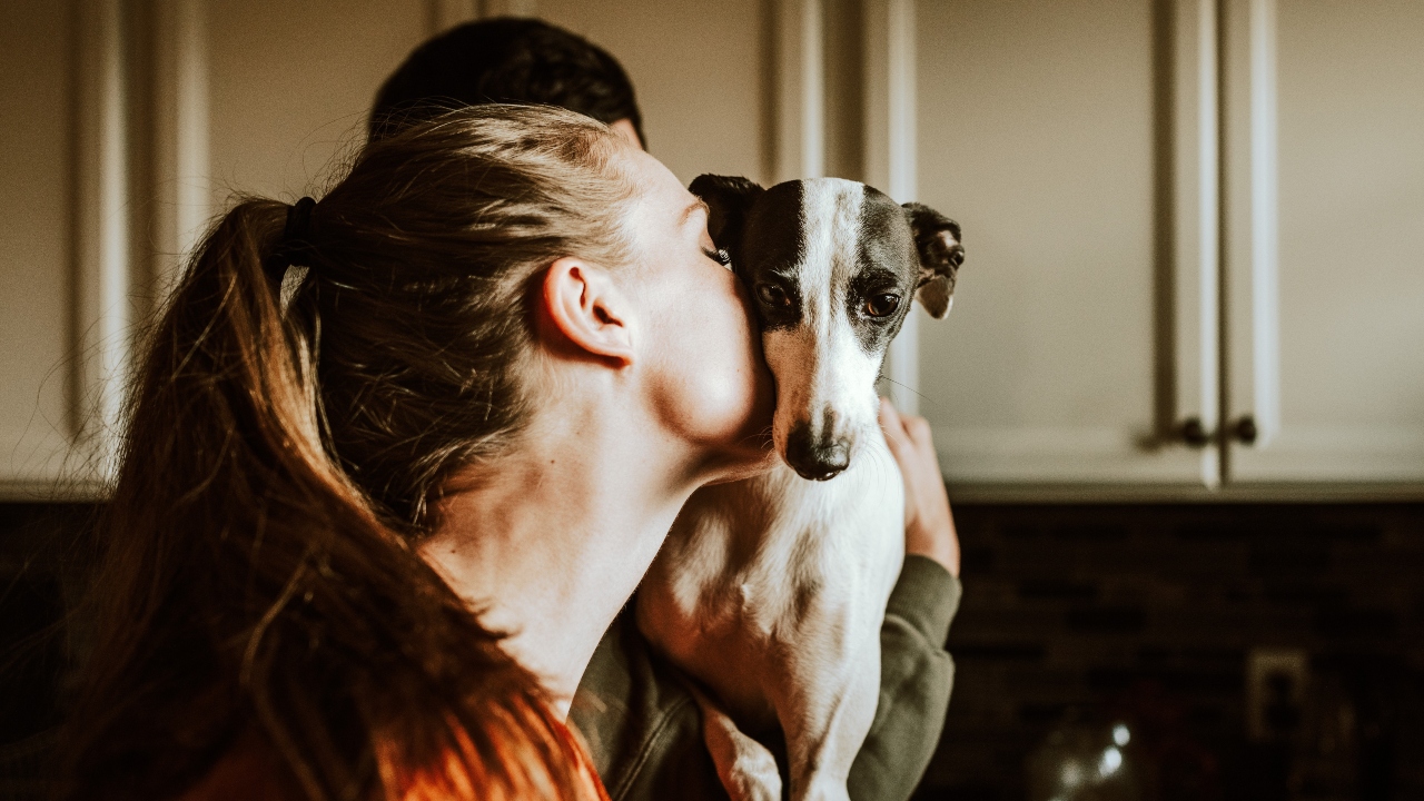 Mujer joven dando un beso a un perro