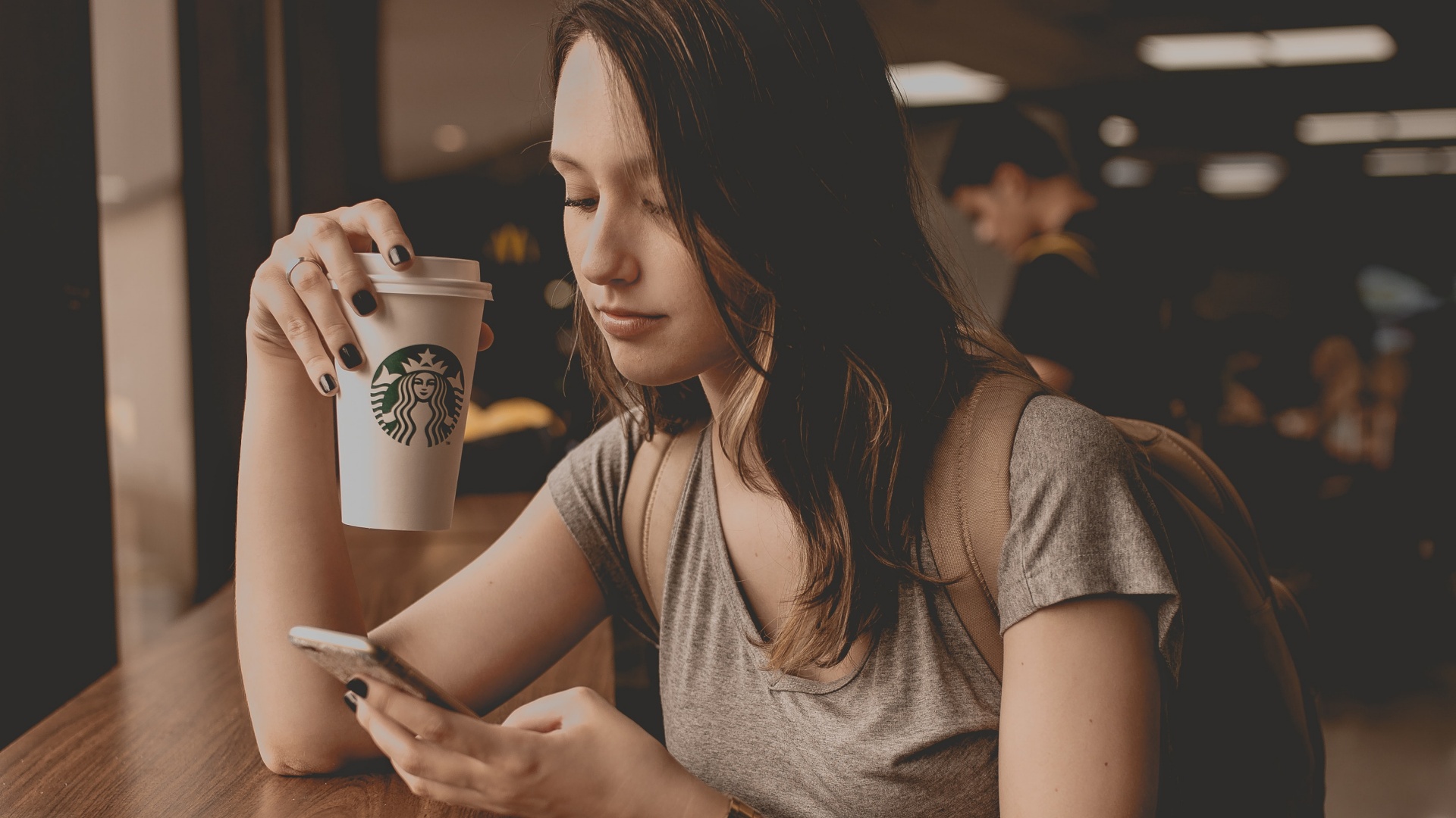 Fiatal lány starbucksos pohárra ül a kávézóban