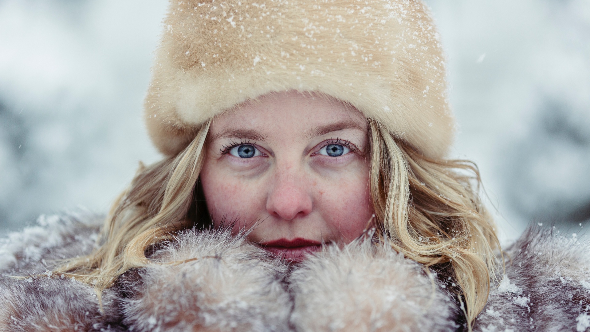 Egy nő bundában és szőrmesapkában a hóesésben