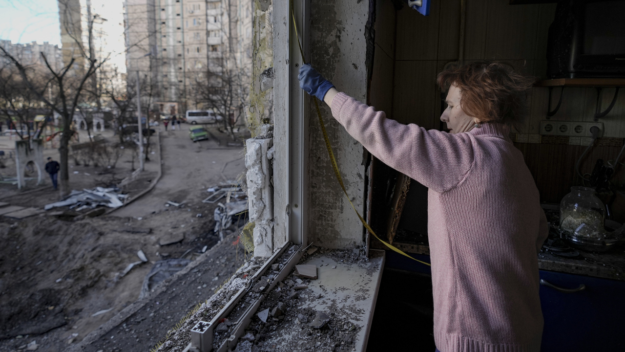 A tüzérségi támadásban súlyosan megrongálódott lakásának ablakát méri egy nő Kijevben / MTI/AP/Vadim Ghirda