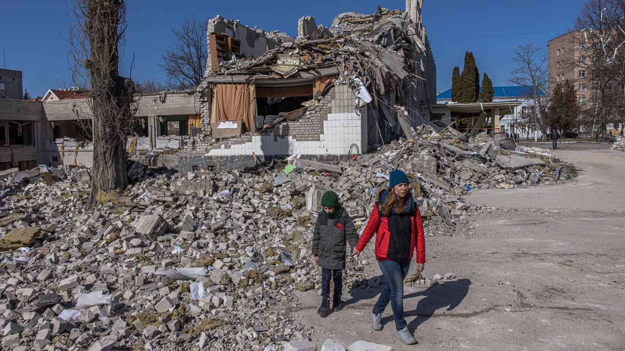 Anya gyermekével egy rommá vált iskolaépületnél a nyugat-ukrajnai Zsitomirban 2022. március 20-án. MTI/EPA/Roman Pilipej