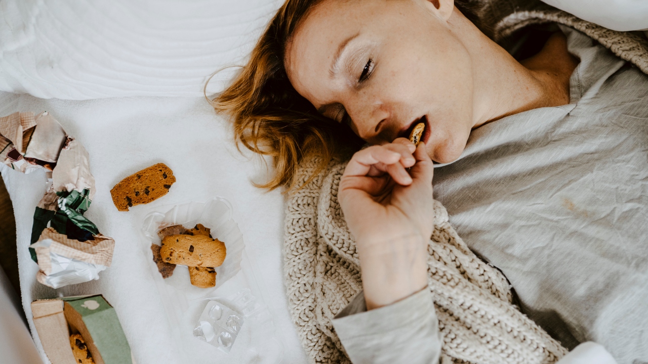 Nő ágyon fekve kekszet eszik