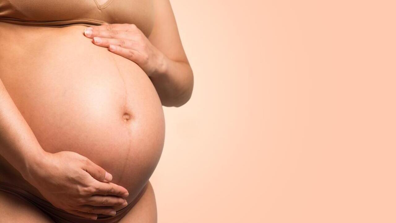 terhes nő fogja a hasát