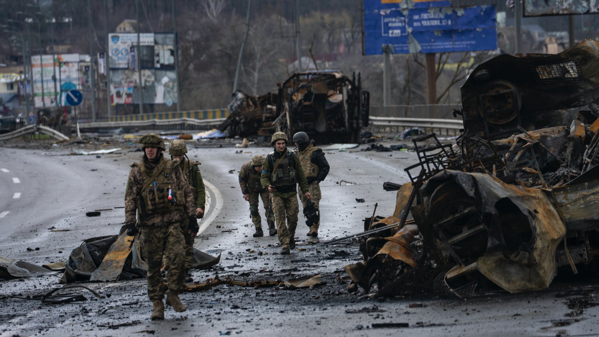 Ukrán katonák megsemmisült orosz páncélozott katonai jármûvek roncsai mellett Bucsában, Kijev közelében 2022. április 2-án