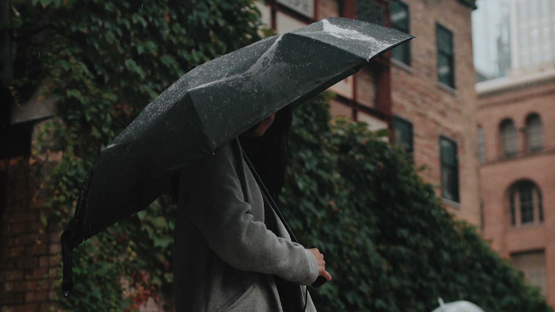 Nagy esernyő alá bújt nő az esőben