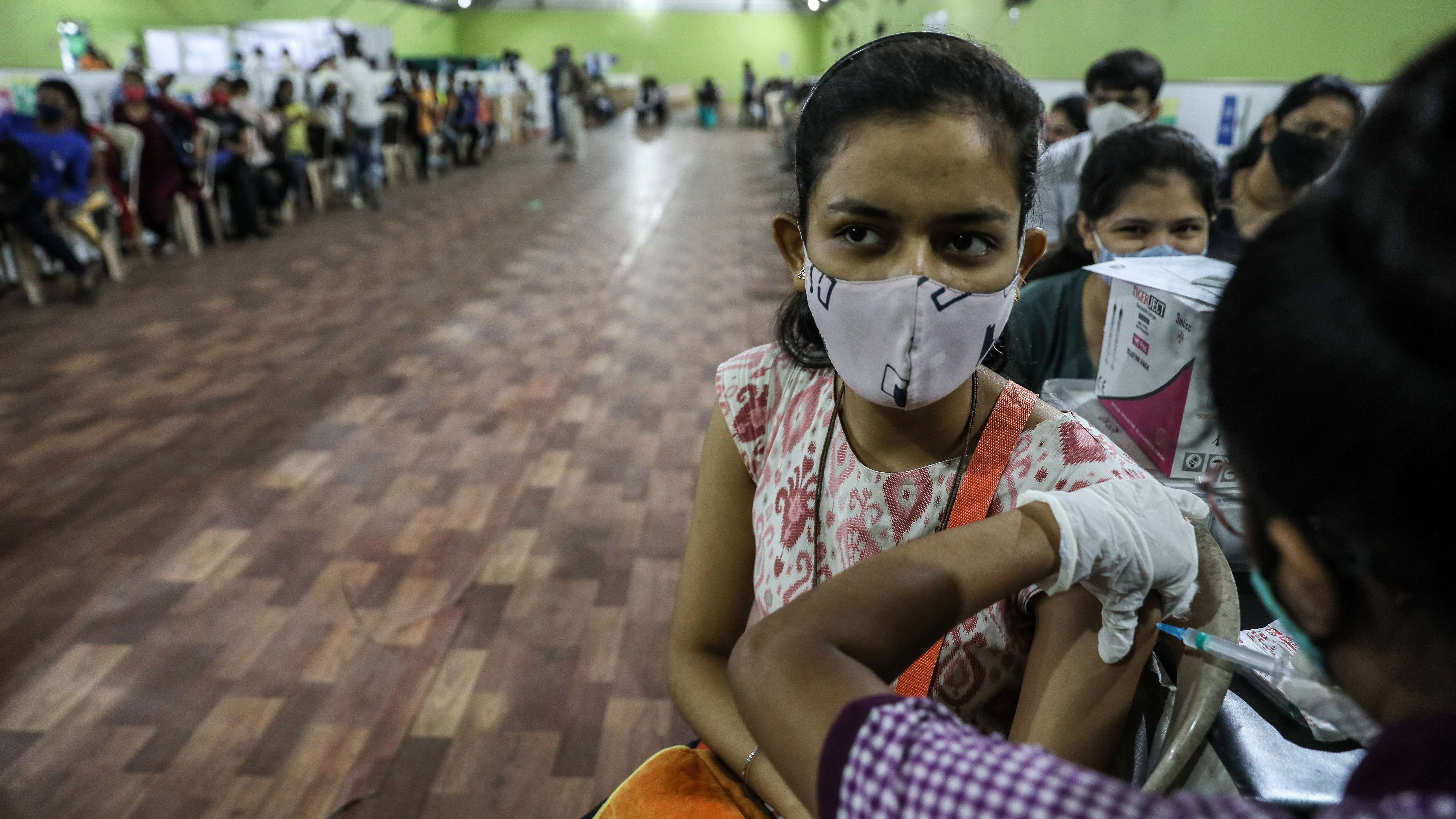 A koronavírus elleni oltás felvételére várnak fiatalok egy oltóközpontban Mumbaiban 2022. január 3-án