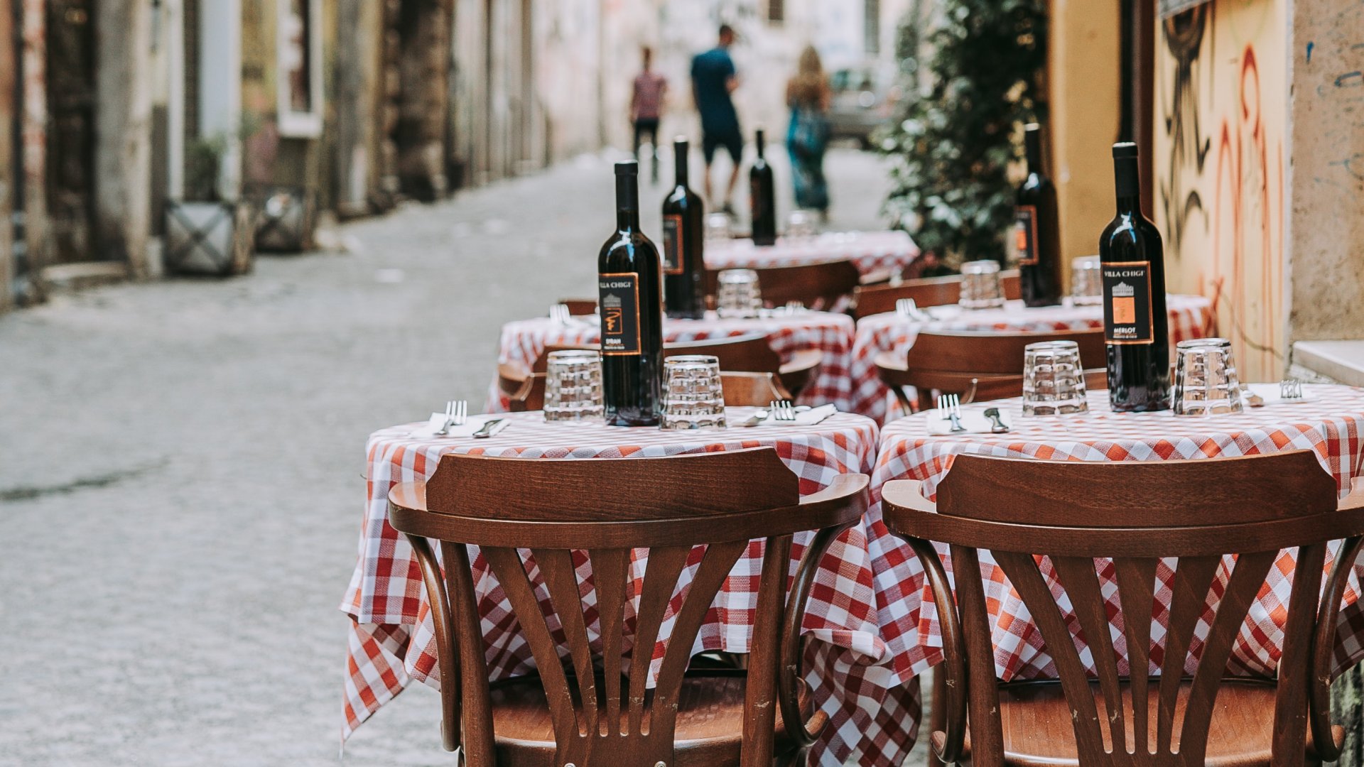 Olaszországi étterem kockás terítős asztalai az utcán