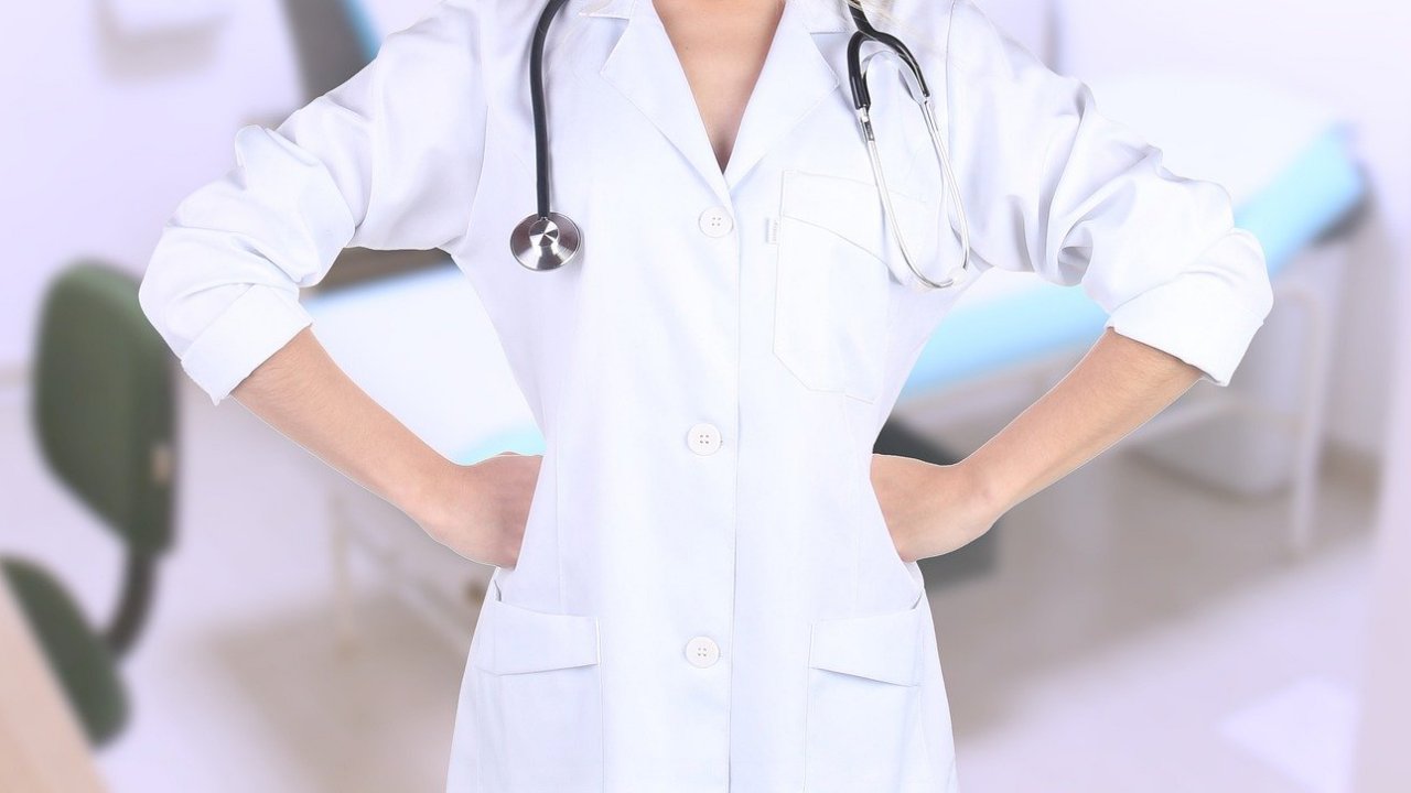 Egy fehér ruhás doktornő csípőre tett kézzel