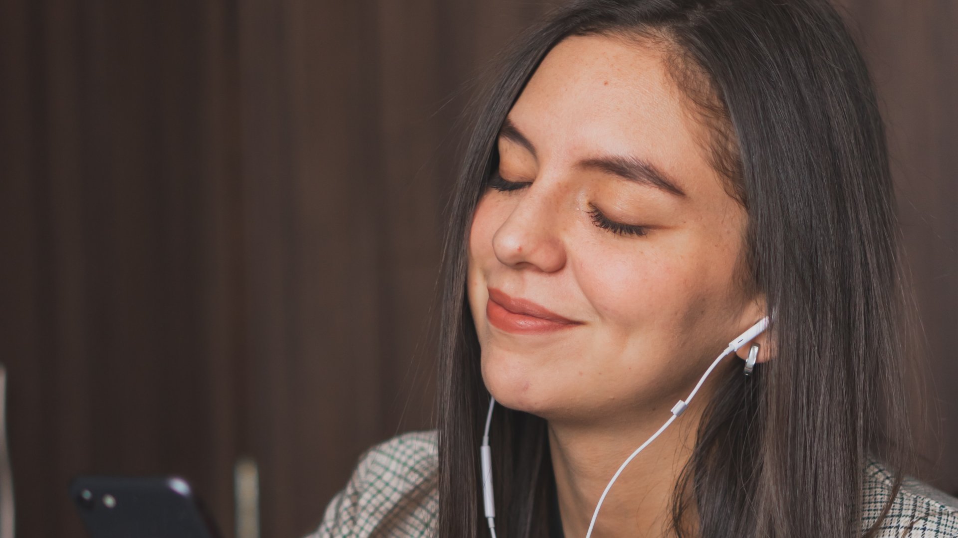 Fülhallgatóval zenét hallgató mosolygó lány
