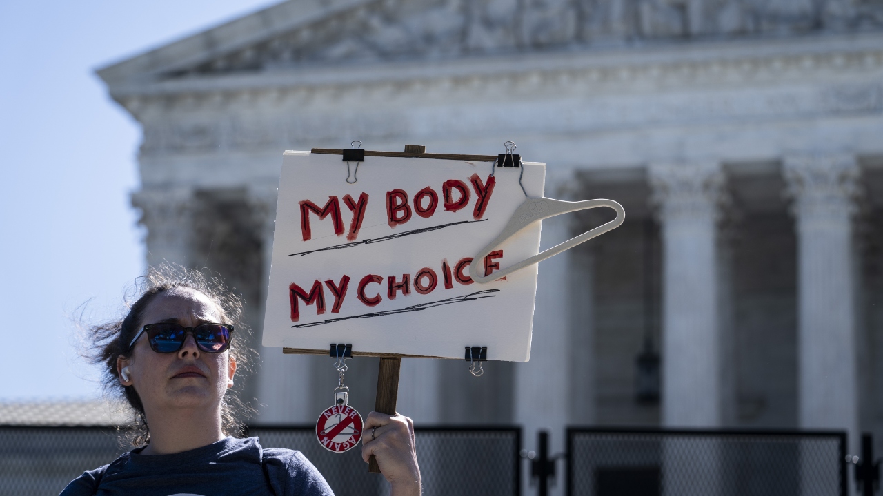 2022.05.11-én egy tüntető a Legfelsőbb Bíróság épülete előtt tartja az "Én testem, én döntésem" feliratú táblát