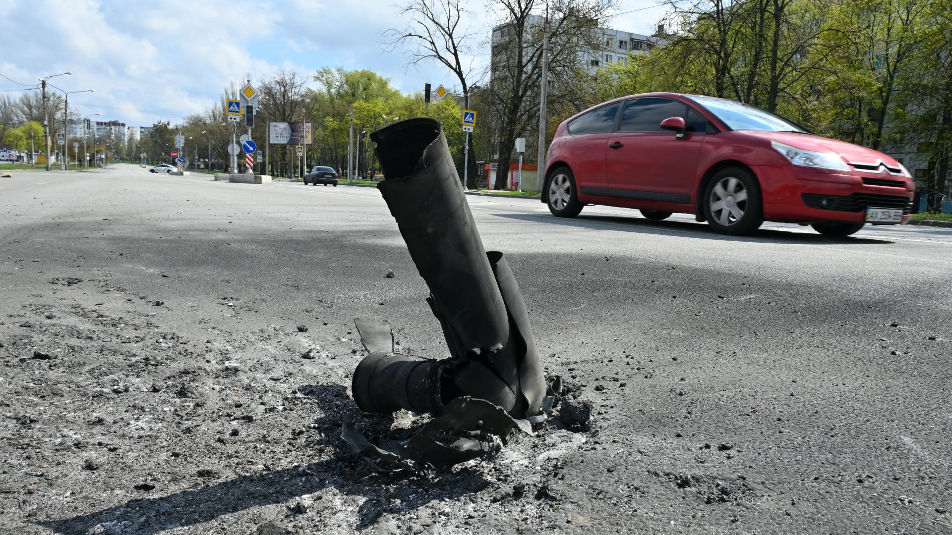Egy autó halad el egy rakéta maradványai mellett egy lakónegyedben Harkivban 2022. április 21-én