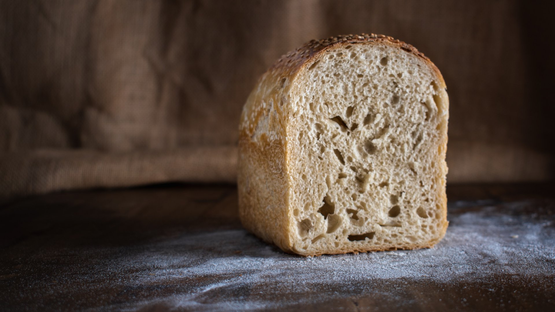 Félbe vágott kenyér a lisztes vágódeszkán