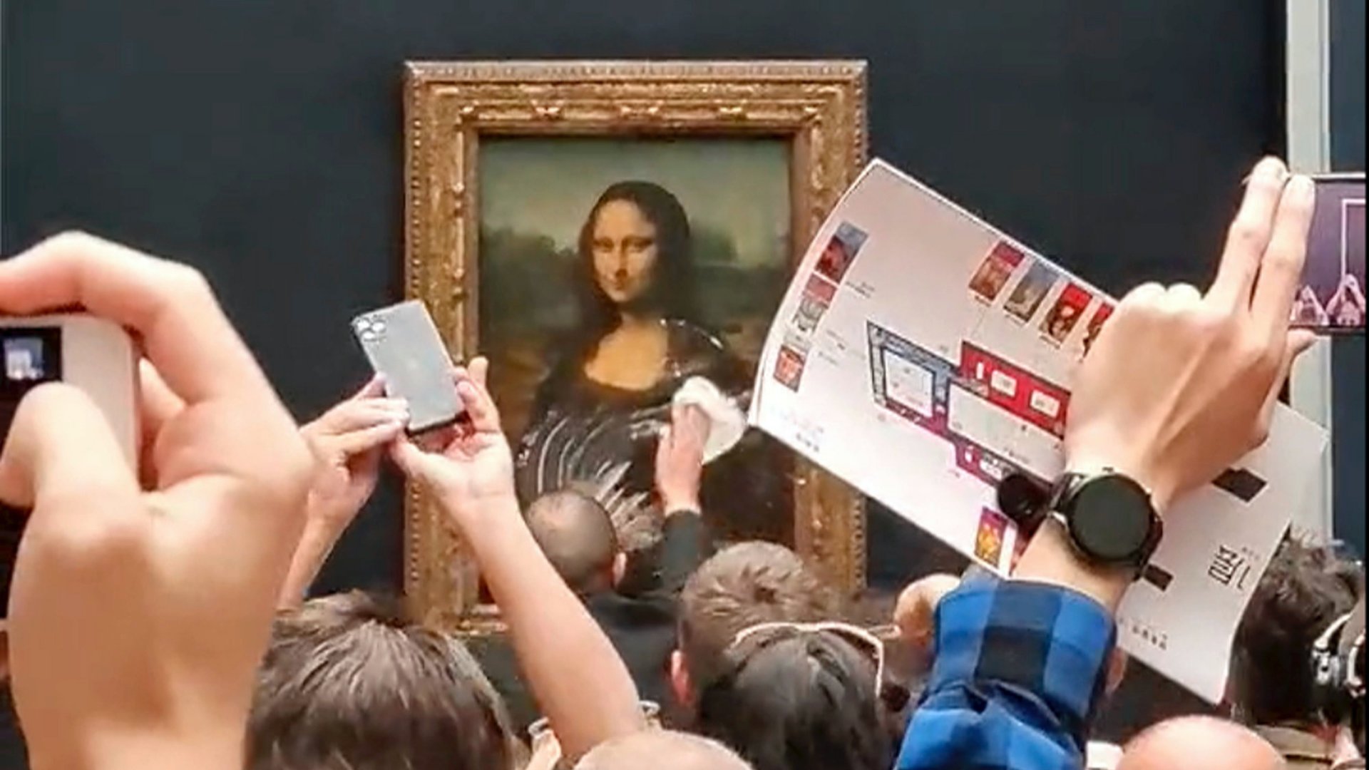 Biztonsági õr takarítja a tortakrémet Leonardo da Vinci olasz mûvész Mona Lisa címû festményének védõüvegérõl a párizsi Louvre múzeumban 2022. május 30-án.