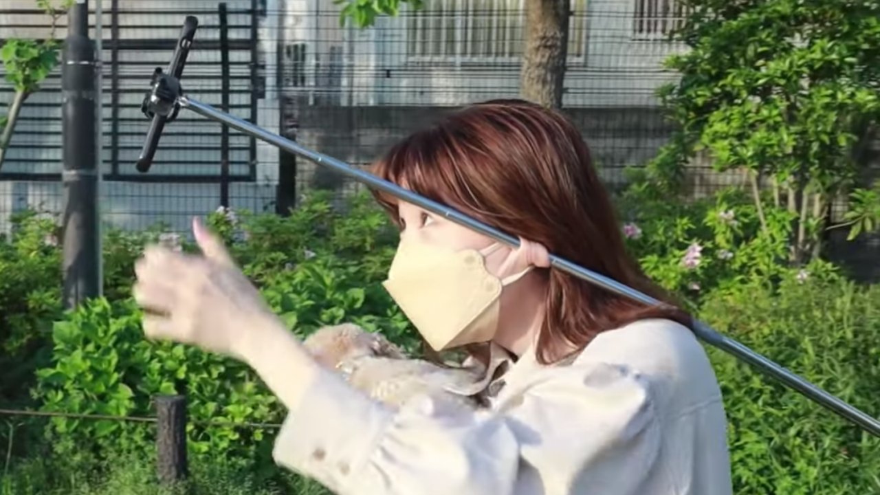 Rugalmas fülcimpájával tart egy szelfibotot egy japán nő