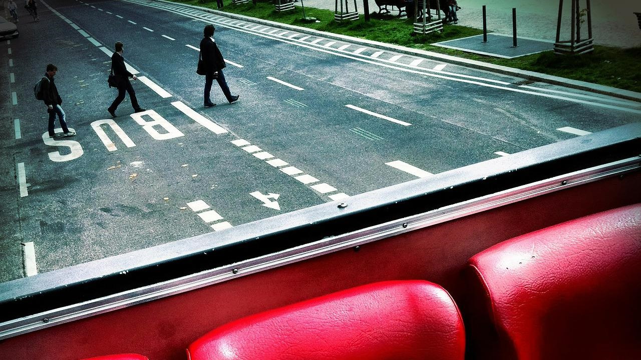 Járókelők kelnek át az úton egy busz mögött