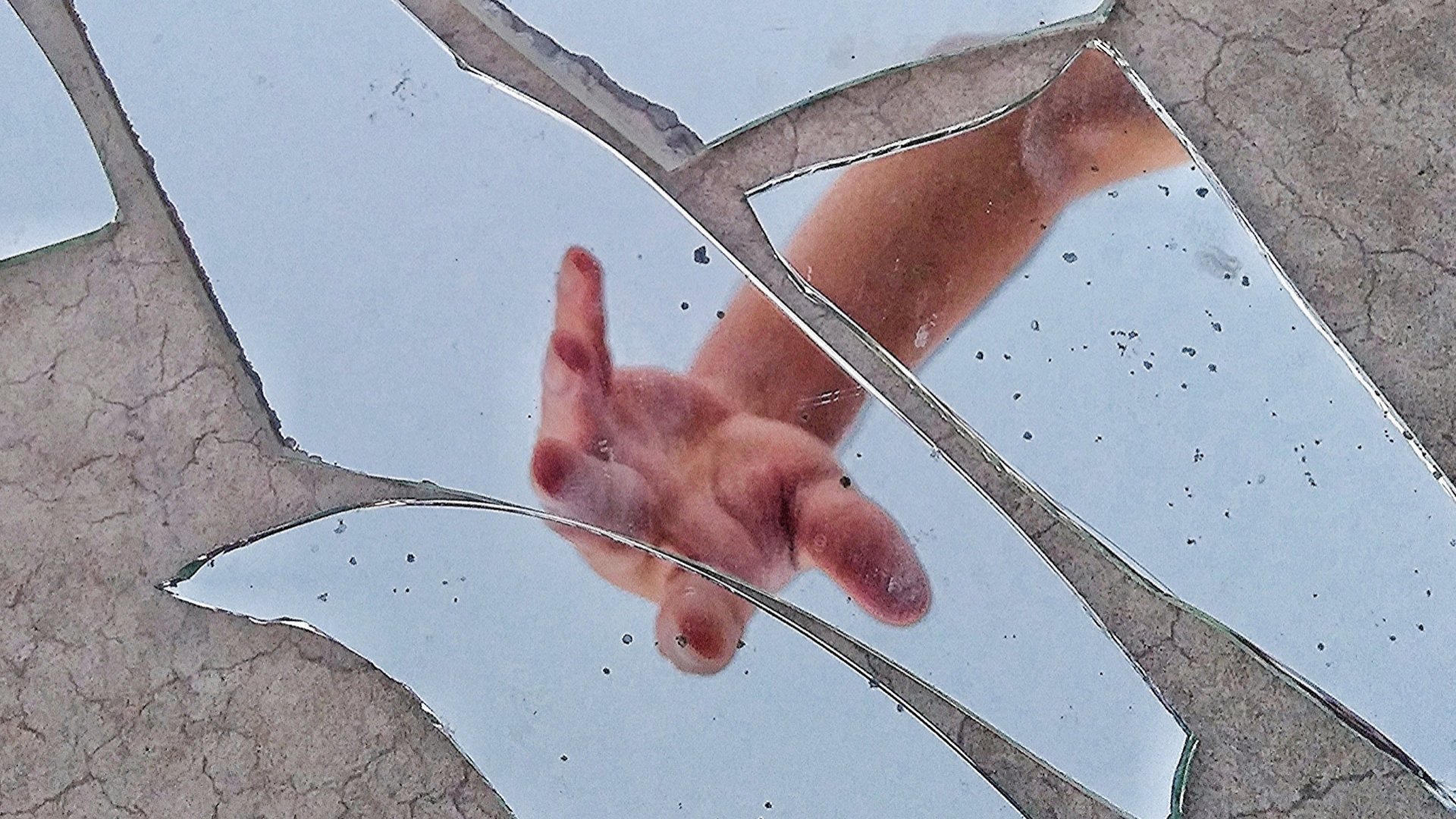 Törött tükörben egy férfi keze