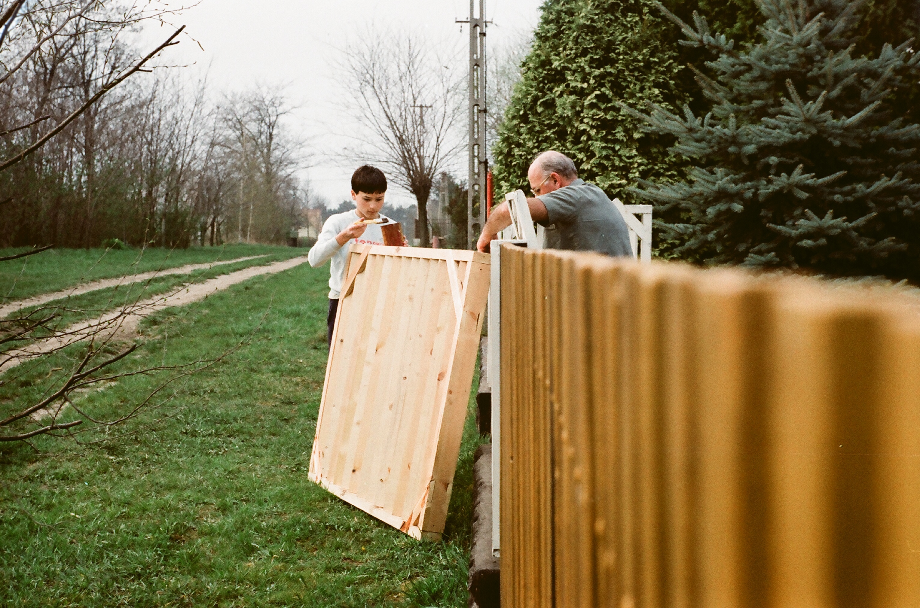 Unoka segít kerítést festeni a nagypapának