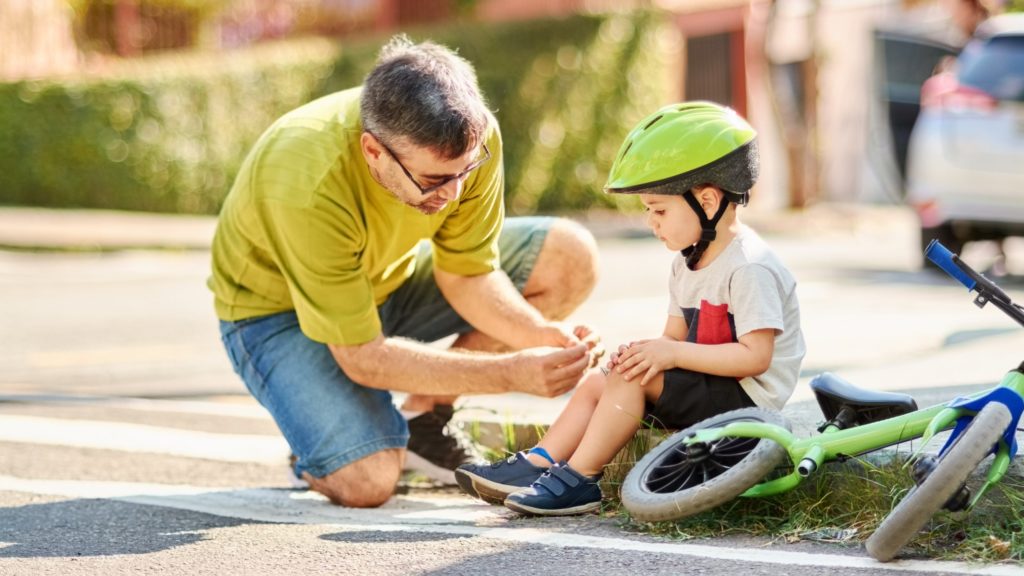 Biciklizés közben megsérült gyermeket lát el az apja