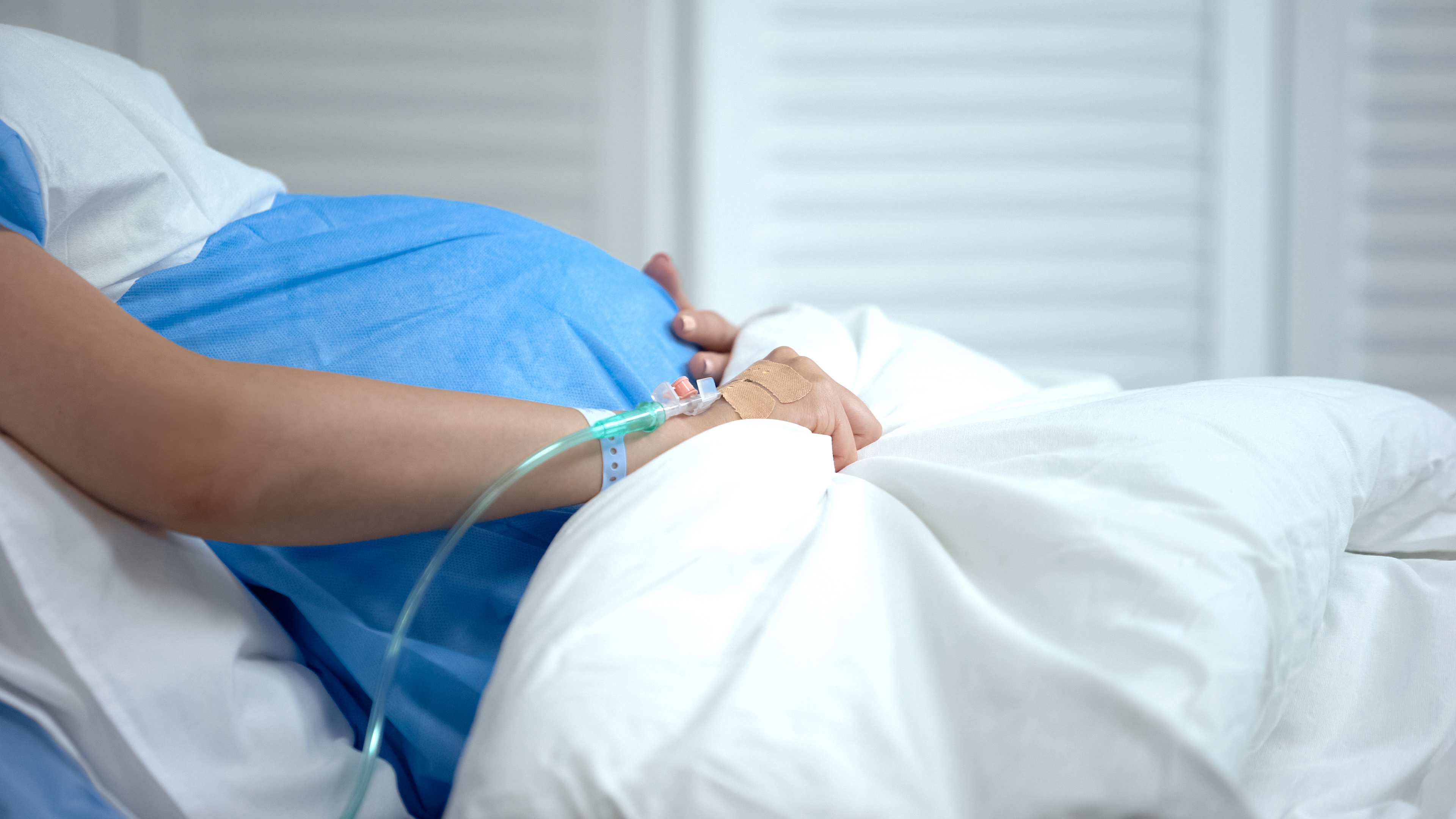Terhes nő fekszik egy kórházi ágyon