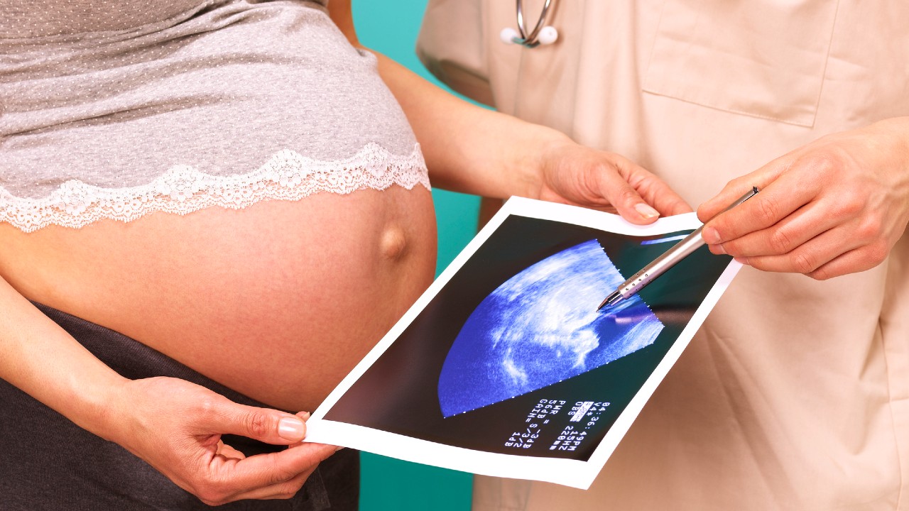 Egy terhes nő ultrahangos képet néz.