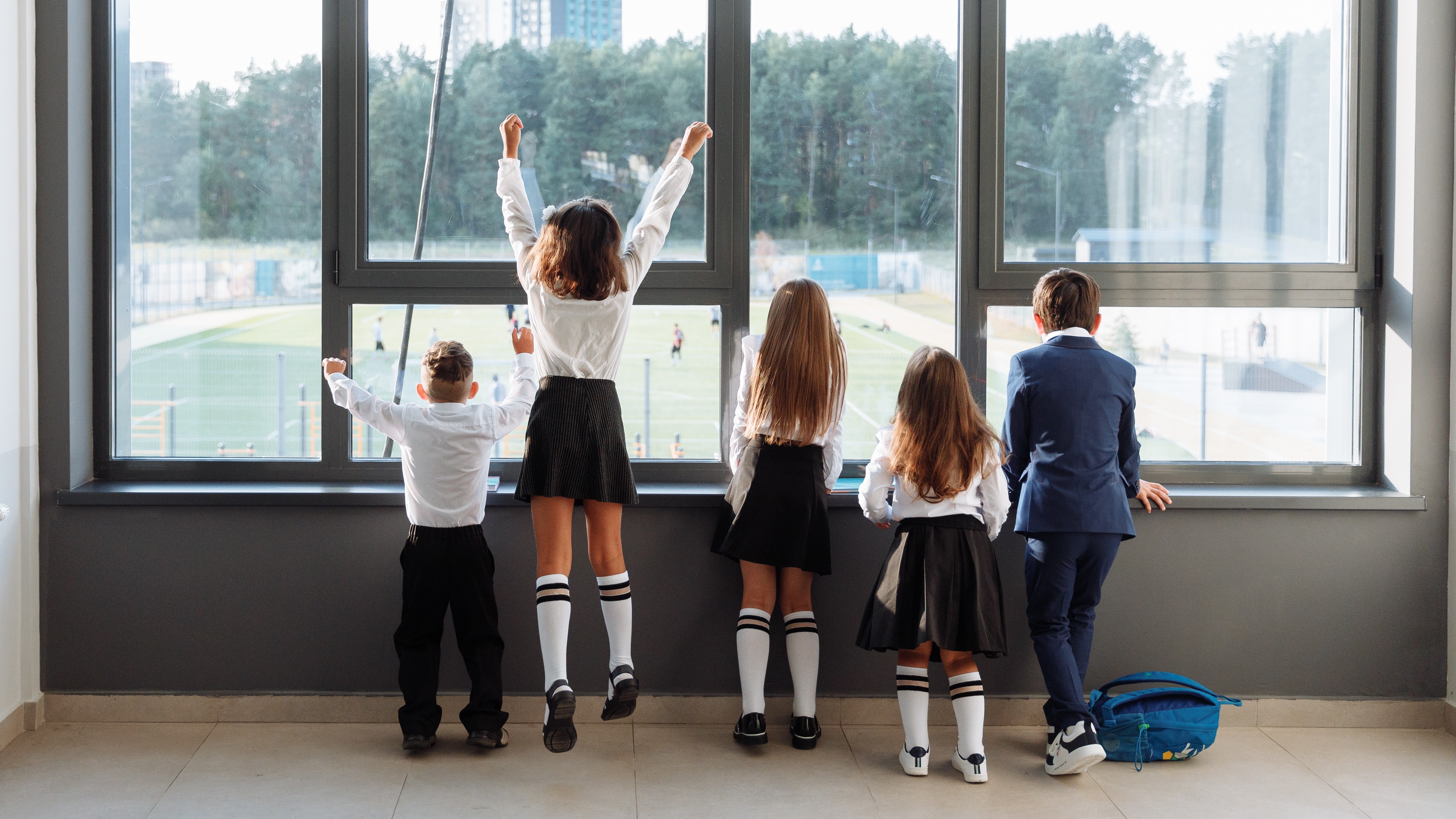 Gyerekek iskolai egyenruhában egy ablak előtt